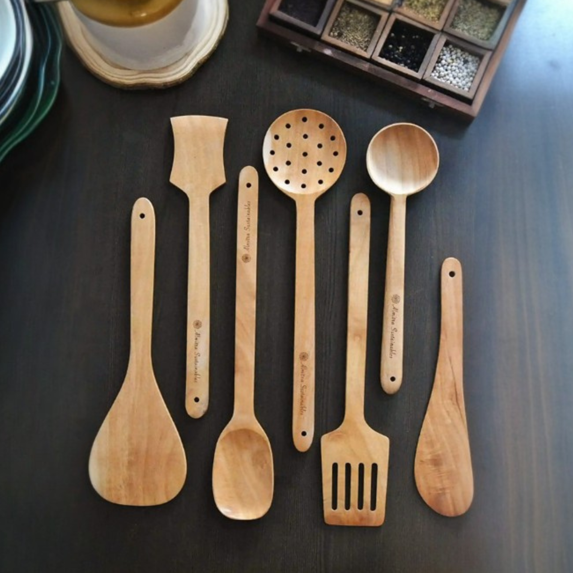 Seven-piece neem wood kitchen utensil set in natural finish with ladles for frying, stirring, serving, and flipping.