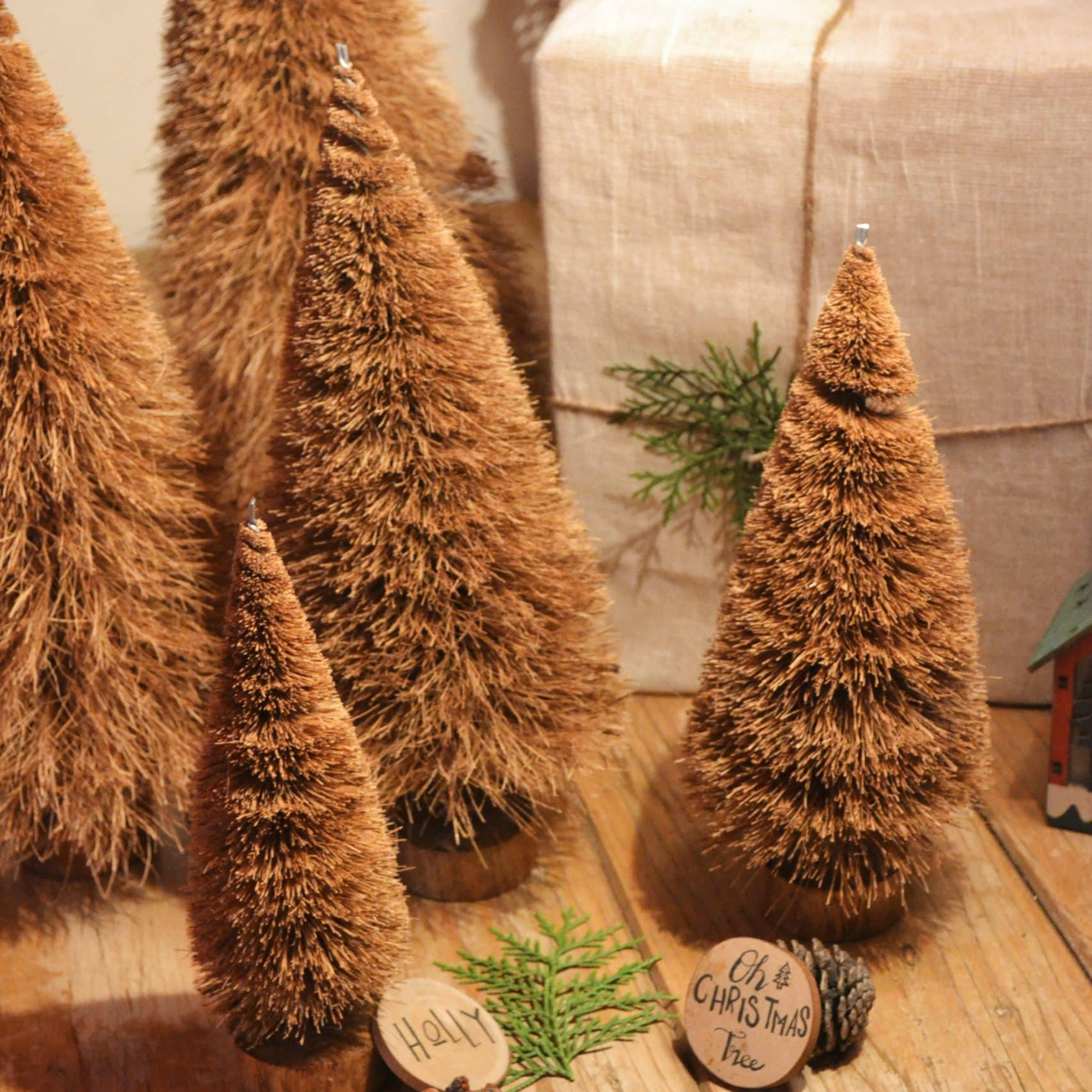 A 25 cm handcrafted Christmas tree made from natural coconut coir fiber and mounted on a rustic wooden base, surrounded by pinecones and eco-friendly holiday decor — sustainable Christmas decoration by Almitra Sustainables.